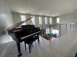 Black Yamaha grand piano on a mezzanine landing with moving boxes below
