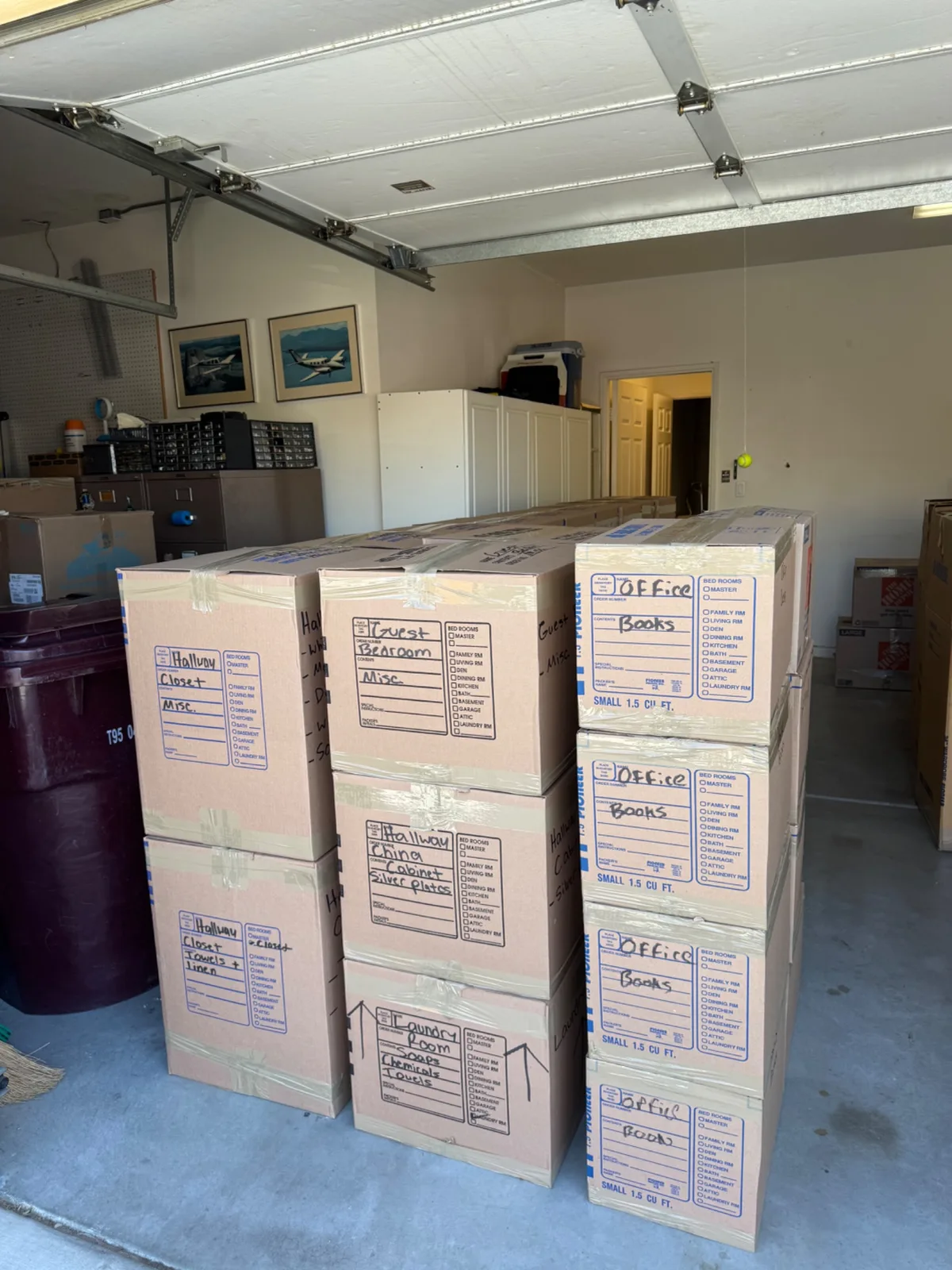 Rows of labeled cardboard moving boxes stacked inside a garage, ready for a move.