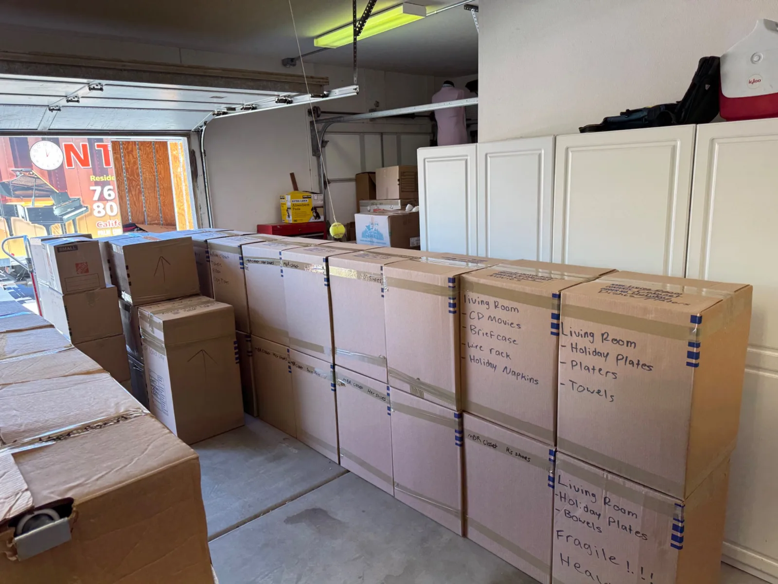 Stacks of cardboard moving boxes with hand-written labels sitting in a garage during a move from Palm Desert to Banning.
