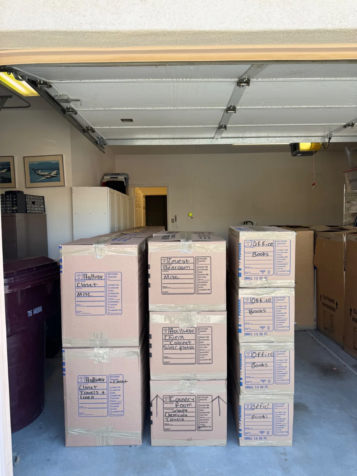 Stacks of labeled cardboard moving boxes neatly arranged in a residential garage.