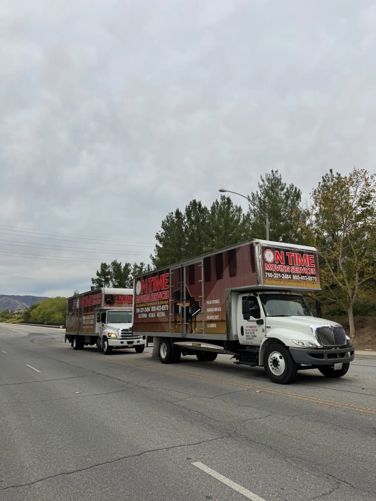 Two branded moving trucks driving on a road during a move between Palm Desert and Banning, California.