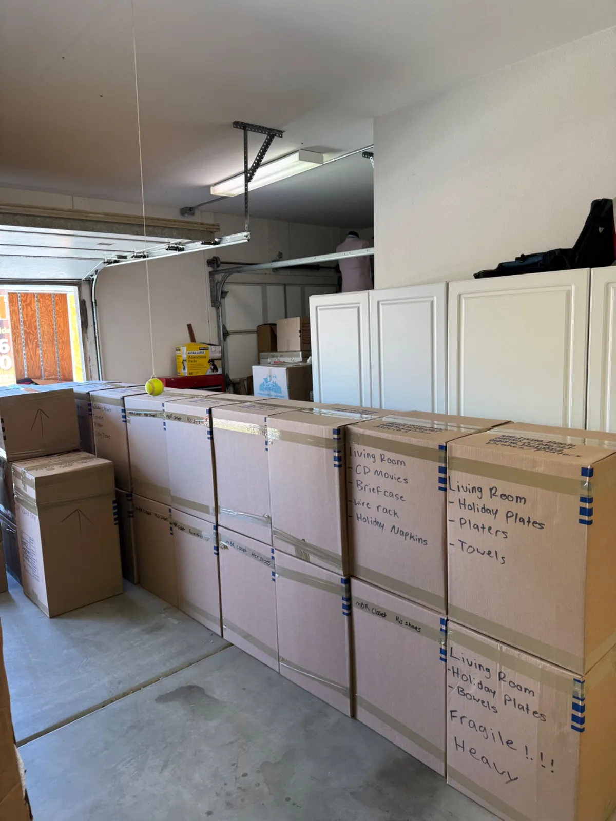Rows of stacked, labeled cardboard moving boxes organized in a garage for a residential move.